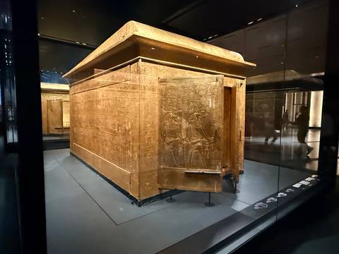 Golden gilded shrine displayed behind glass in the Grand Egyptian Museum.