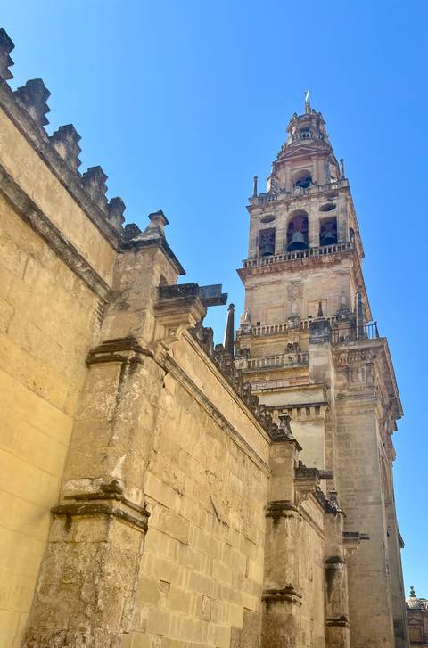 Bell tower of the Mosque-Cathedral of Córdoba rises against a clear blue sky.