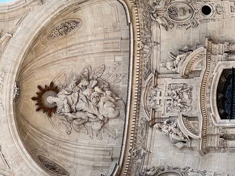 Ornate baroque stone relief depicting religious figures above a cathedral entrance.