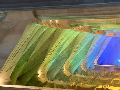 Color-washed interior columns of the Sagrada Familia illuminated by multi-hued stained glass.