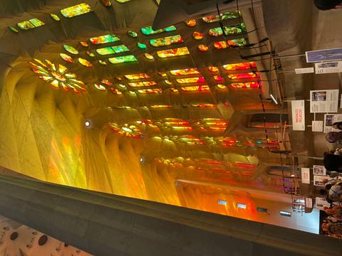 Golden stained-glass light floods the lofty nave of the Sagrada Familia crowded with visitors.