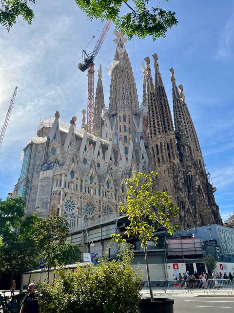 Exterior view of the towering spires and intricate façades of the Sagrada Familia under blue sky.