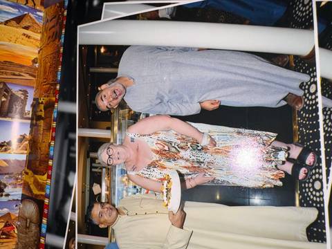 Casual snapshot of cruise staff and passengers indoors celebrating with a cake, flash reflections visible.