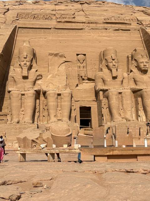 Close-up view of the colossal seated statues at the entrance of Abu Simbel Temple bathed in bright sunlight.