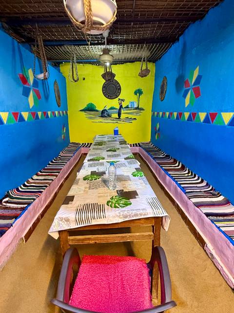 Colorful low dining room with patterned cushions lining benches around two long tables.