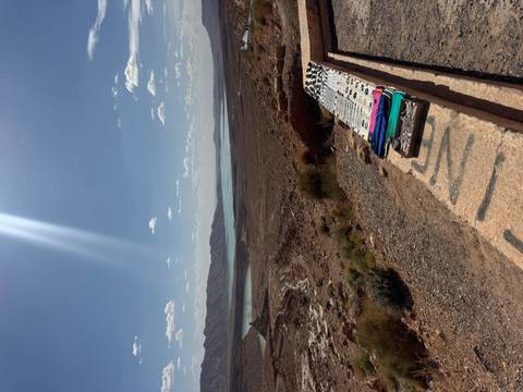 Arid plateau overlooks a shimmering reservoir with handicrafts laid out on a stone ledge in the foreground.