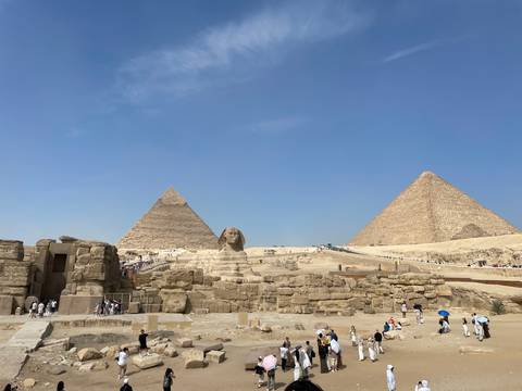 Iconic Pyramids of Giza and the Sphinx rise from golden sands under a flawless blue sky.