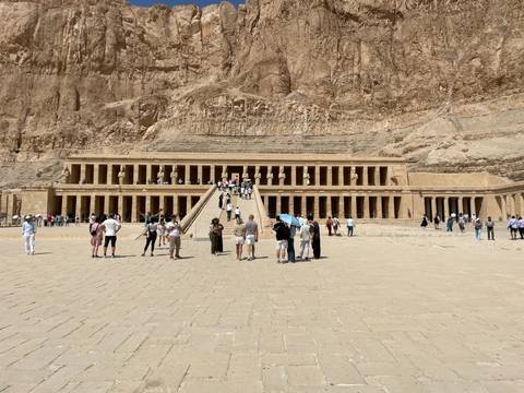 Visitors approach the terraced colonnades of Hatshepsut Temple set against towering desert cliffs.