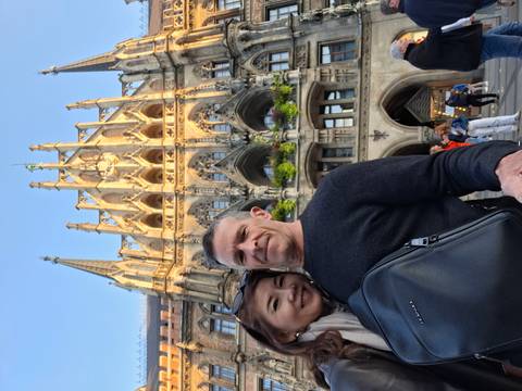 Couple selfie in front of Munich’s ornate Neues Rathaus bathed in warm evening light.