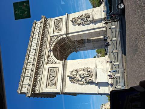 Clear daytime view of the Arc de Triomphe framed against deep blue sky.