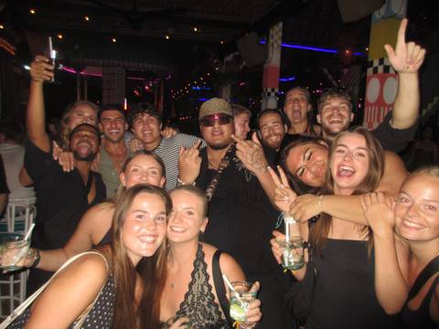 Crowded party photo of happy young travelers posing inside a lively nightclub