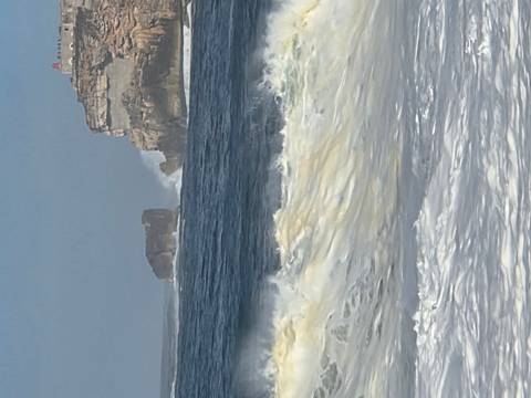 Powerful Atlantic waves crashing below the cliffs and lighthouse near Nazaré.