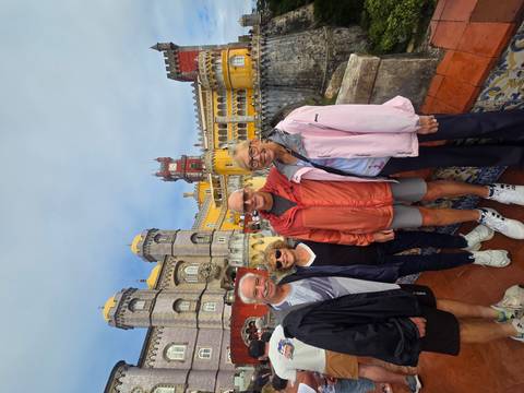 Smiling tour group posing in front of the colorful Pena Palace terraces.