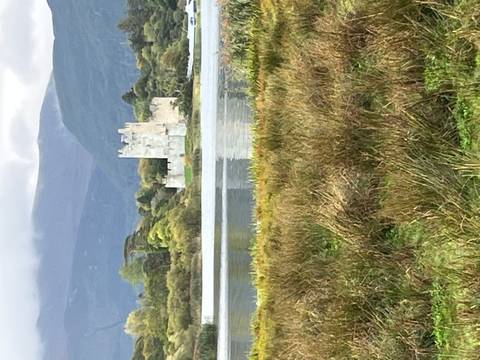 Stone tower castle reflected in a calm lake surrounded by autumn foliage.