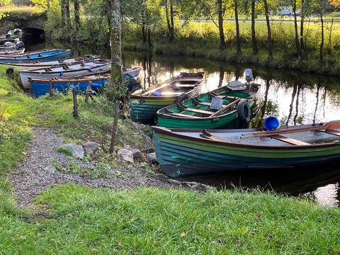 Row of traditional wooden rowing boats moored along a quiet reflective canal.