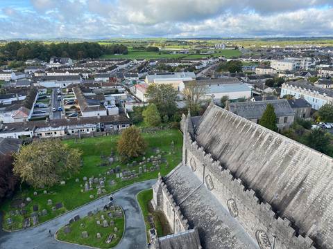High viewpoint overlooking Kilkenny rooftops, gravestones and surrounding countryside under clear sky.