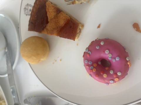 Close-up of a dessert plate featuring a pink iced mini-doughnut, pastry slice and small round cake.
