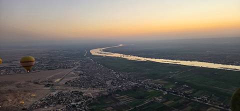 Aerial dawn view of the Nile River winding through farmland with a single hot-air balloon drifting to the side.