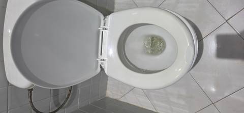 Close-up of a toilet bowl and tiled bathroom floor.
