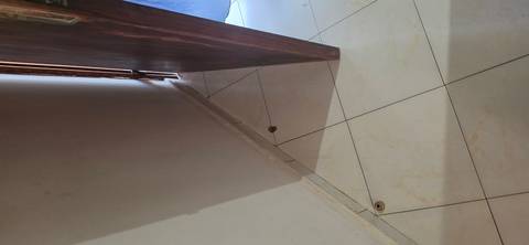 Partially open wooden door and tiled floor corner in a dim hallway.