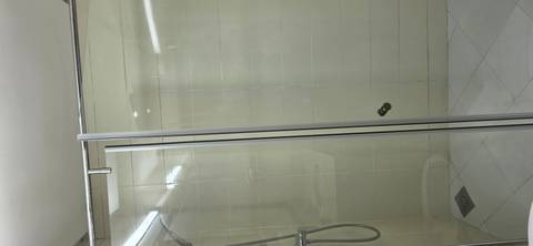 Glass-enclosed shower stall with tiled walls and chrome fixtures.