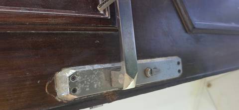 Close-up of a worn metallic door handle on a dark wooden door.