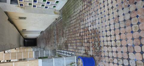 Long covered walkway with patterned mosaic floor tiles and white walls.