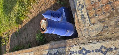 Blue ceramic garden container used as a trash bin beside patterned walkway.