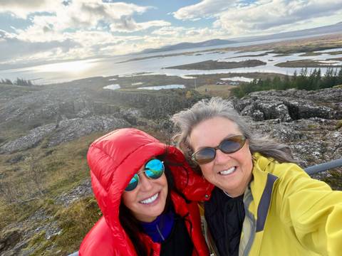 Selfie of two friends with windswept lake, islands and low sun in background.