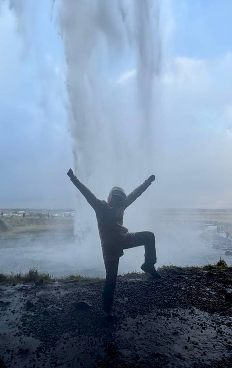 Back-lit silhouette celebrates beside the erupting plume of a powerful geyser.