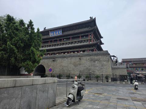 Historic grey-brick Drum Tower in Xi'an fronted by a quiet plaza and parked scooters.