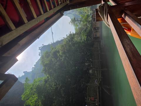 Green river gorge viewed from the shaded deck of a wooden boat with steep forested cliffs towering above.