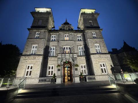 A grand Victorian hotel illuminated at night against a deep blue sky.