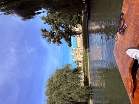 View from a punt gliding along the River Cam toward the gothic towers of King's College framed by willow trees.