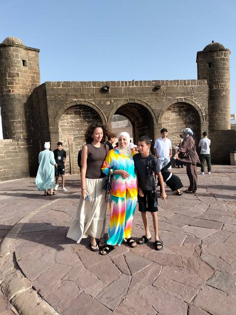Family and other visitors pose near a stone fortress archway on a sunny day.