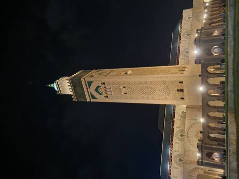 The illuminated minaret and façade of the Hassan II Mosque stand majestically against the night sky.