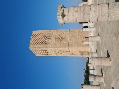 The sandstone Hassan Tower rises under a vivid blue sky, surrounded by rows of unfinished columns.