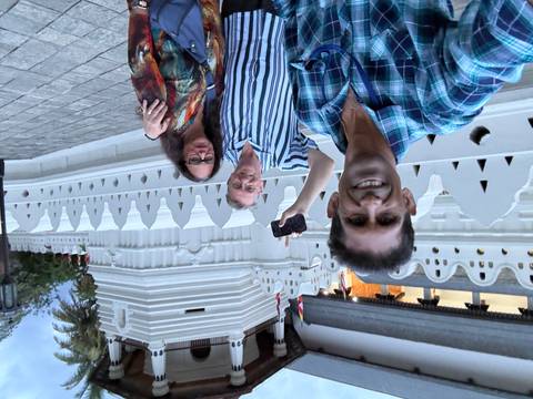 A guide takes a selfie with two travellers in front of the white-walled Temple of the Tooth in Kandy, Sri Lanka.