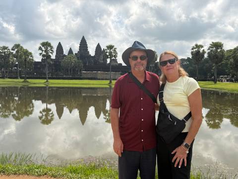 Couple posing by the reflecting pond with the towers of Angkor Wat rising behind them.