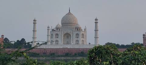 Classic frontal view of the white marble Taj Mahal framed by greenery.