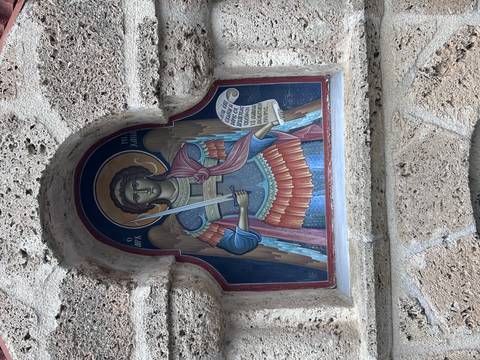 Colorful religious fresco of Archangel Michael framed in a stone niche.