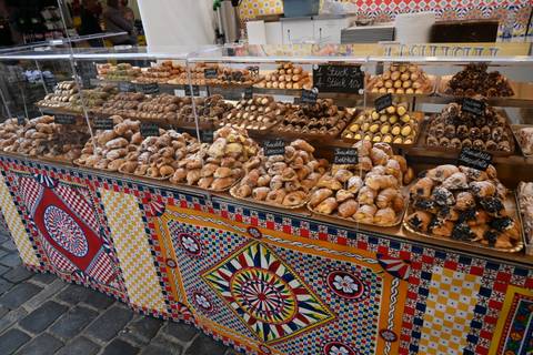 Colorful outdoor bakery stall displaying a wide array of pastries and sweets at a market.