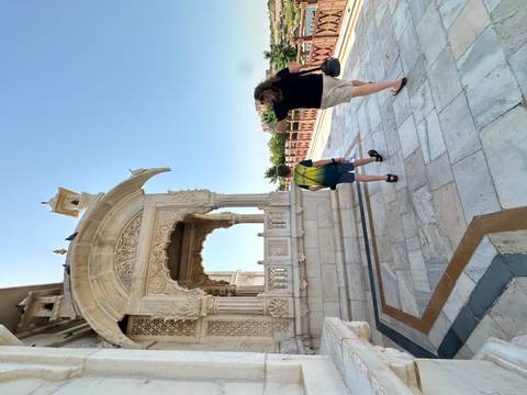 Mother and son explore an ornate white marble cenotaph on a bright clear day.