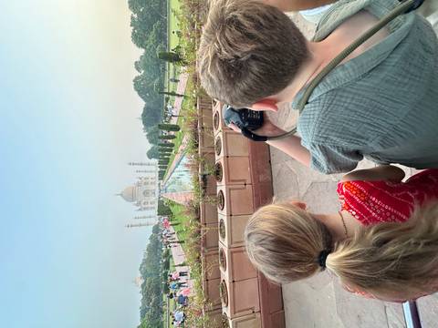 Two children view and photograph the Taj Mahal from the reflecting pool walkway.