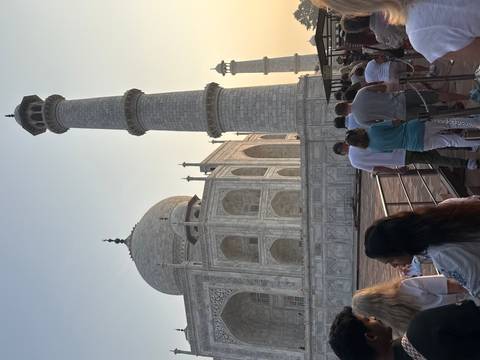 Line of tourists waiting beside the Taj Mahal’s marble terrace and minaret at sunrise.