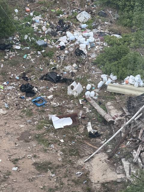An area strewn with household rubbish, plastic bottles and scrap wood.