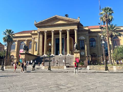 Grand neoclassical Teatro Massimo opera house in Palermo with visitors on the broad steps.