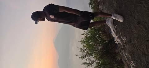 A traveler gazes at a misty volcanic lake and peak during sunrise.