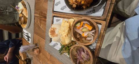Traditional Indonesian meal served on wooden trays with assorted side dishes.