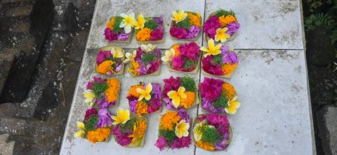 Colorful Balinese flower offerings neatly arranged on white stone tiles.